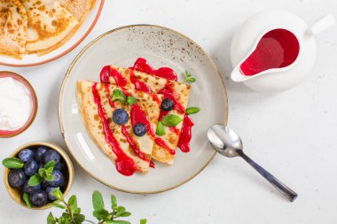 Çilek soslu krep ve yaban mersini tabağında.