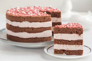 Kremalı ve ahududulu ev yapımı çikolatalı pasta, beyaz masada pembe süsleme. Ev yapımı..