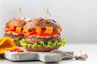 Quinoa, fasulye, fıstık sosu, salata ve domatesten yapılmış iki vejetaryen burger. Hafif arkaplan, boşluğu kopyala.