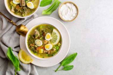 Et suyu çorbasından, kızamık yapraklarından, haşlanmış bıldırcın yumurtalarından, patateslerden, havuçlardan, maydanozdan yapılır. Açık gri arkaplan. Boşluğu kopyala