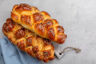 Ev yapımı Challah ekmeği, susam tohumuyla süslenmiş. Üst Manzara. Açık gri arkaplan. Boşluğu kopyala.