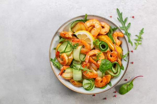 Izgara karides, karamelize armut, salatalık ve limon soslu karışık yeşil salata. Açık gri arkaplan. Üst görünüm.