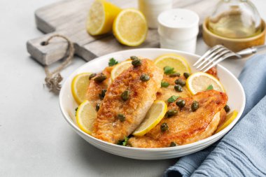 Chicken piccata on white table. Chicken breast dredged in flour and cooked in sauce cantaining lemon juice, butter and capers.  clipart