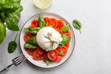 Domates ve fesleğen yapraklı burrata peyniri. Caprese salatası. Tam üstte, aydınlık masa..