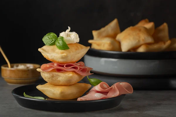 İtalyan usulü kızarmış ekmek kreşenli ya da mortadella ve yumuşak peynirli gnocco fritto, fesleğen yapraklarıyla süslenmiş. Geleneksel Bologna mezesi. Koyu arkaplan.