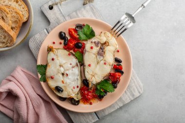 Domates ve siyah zeytinle pişirilmiş balık bifteği yemek. Sağlıklı yiyecekler. Gri arkaplan, üst görünüm, kopyalama alanı.