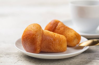 Rum baba ya da baba au rhum 'a yakın çekim. Romlu şurupla doldurulmuş küçük maya keki. Seçici odaklanma. Hafif arkaplan.
