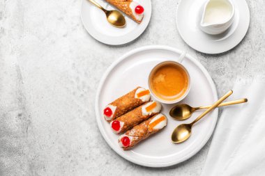 İtalyan pastalı cannoli ve ricotta kremalı kahvaltı. Kahve fincanı, beyaz taş arka planda. Boşluğu kopyala.