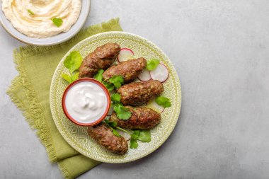 Yoğurtlu biftek, taze kişniş ve humus. Gri arkaplan.