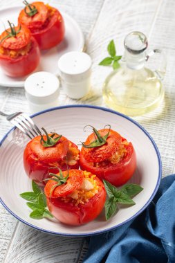 Pirinç ve peynirli domates dolması, fırın. Beyaz ahşap yüzey, dikey görüntü.