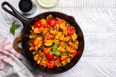 Sotelenmiş kabak, dolmalık biber, havuç ve soğan. Koyu ahşap bir masada domates sosu, üst manzara..