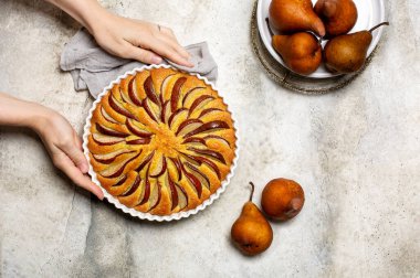 Kadının eli az önce kahverengi armutlu turta yaptı. Işık arkaplanı, kopyalama alanı. Boşluğu kopyala.