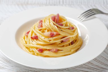 Beyaz tabakta spagetti carbonara. Spagetti, pancetta ve yumurta sarısı, parmesan peyniri ve karabiberden yapılmış sos. Yakın plan..