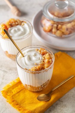 Karamelli tarçınlı, elma ve cevizli Yunan yoğurdu. Dikey resim.
