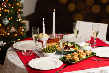 Noel arifesi, ev yapımı yemekler, kanepe, karides ve guacamole turtaları, kış salatası, zeytin, yunan balığı, beyaz şaraplı bardaklar. Arka planda Noel ağacı olan bir ev. Akşam yemeği partisinin yaşam tarzı foto.