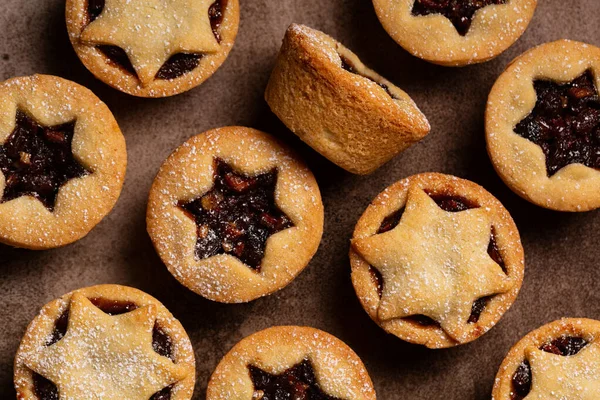 Kahverengi yiyecek arka planında geleneksel İngiliz noel tatlısı üzerine şeker serpiştirilmiş kahverengi bir tepside kıymalı turta. Meyve, baharat ve suet karışımı ile doldurulmuş kıymalı ya da meyveli turta da denir. Yatay resim.