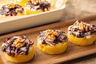 Polenta mini keklere bölündü ve yumuşak peynir, radicchio ve cevizle pişirildi. İtalyan yemeklerini kapatın..