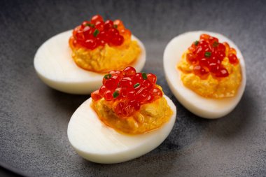 Baharatlı yumurta ve gri tabakta somon havyarı..