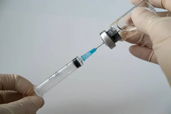 Doktor aşıyı çevirir. Hemşire aşıyı şişelerden şırıngaya çeviriyor.