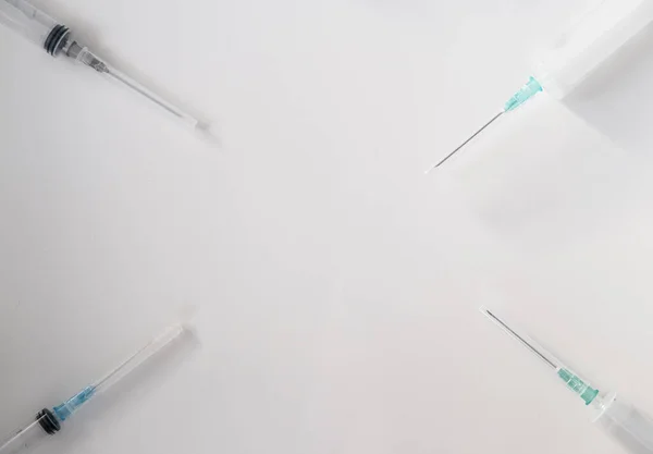 Farklı hacimli şırıngalar köşelerdeki beyaz arka planda yatar