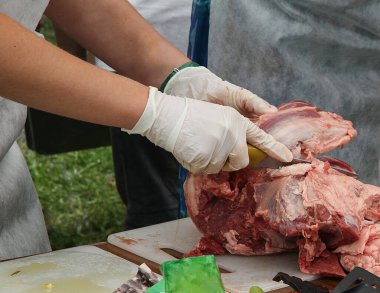 Erkek eli eldivenli, sokakta et kesiyor.