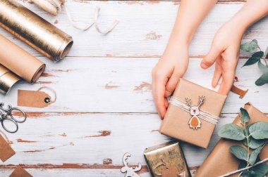 Elleri hediyeli, geri dönüştürülmüş kahverengi kağıda sarılmış, el yapımı üst kaplamalı, minimalist stil ambalajlı Noel arkaplanı, üst görünüm düz.