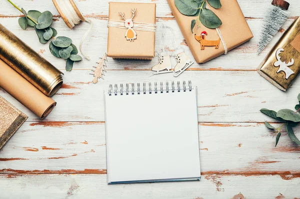 Xmasの願いを書くための空の開いているノートブック 手作りのトッパーで再生茶色の紙に包まれた贈り物 ミニマルなスタイルの包装でクリスマスの背景 — ストック写真