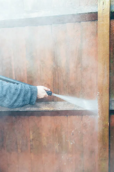 Очистка деревянного забора с помощью мойки под давлением — стоковое фото
