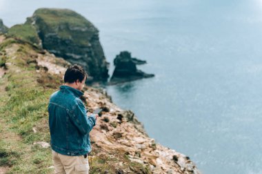 Adam İrlanda denizinde uçurumun kenarında duruyor.
