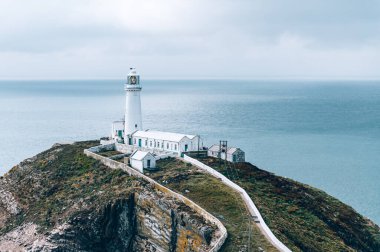 South Stack Deniz Feneri, Galler, Anglesey, İngiltere. Kutsal Ada 'nın kuzey-batı kıyısında küçük bir adanın zirvesine inşa edilmiştir. Gemileri aşağıdaki tehlikeli kayalara karşı uyarmak için 1809 'da inşa edildi..