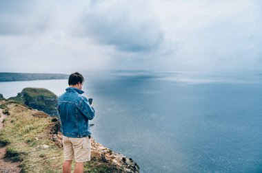 Adam İrlanda denizinde uçurumun kenarında duruyor.
