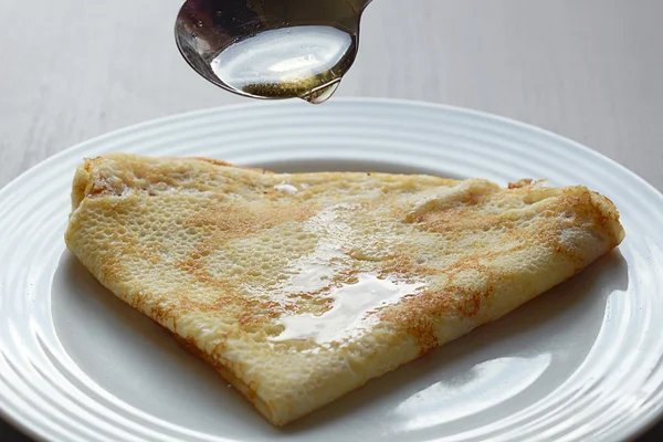 Nahaufnahme des Gießens von Honig auf leckeren Pfannkuchen — Stockfoto