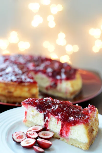 Segment van Cranberry vanille Cheesecake met lichten op achtergrond — Stockfoto