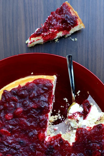 Клюквенный ванильный чизкейк на красной тарелке с чайной ложкой — стоковое фото