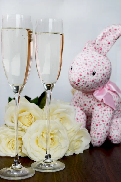 Champagneglas, låda med choklad, massa vita rosor och rosa Hare — Stockfoto