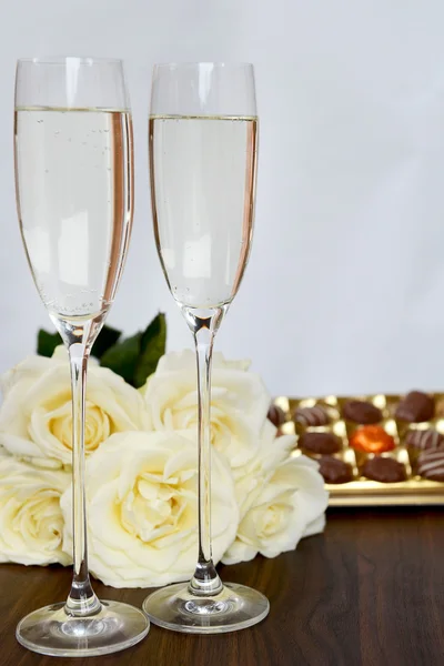 Champagneglazen, doos van chocolade en bos van witte Roses — Stockfoto
