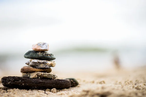 Pyramide de pierres sur sable. La mer en arrière-plan — Photo