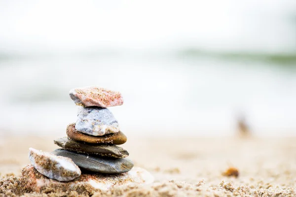 Kövek piramis a homok. A tenger a háttérben — Stock Fotó