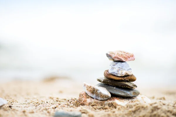 Kövek piramis a homok. A tenger a háttérben — Stock Fotó