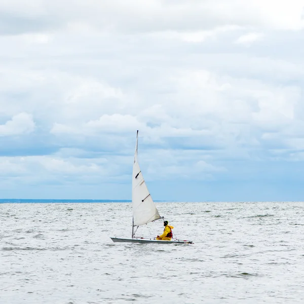 Ensam segelbåt i havet, molnig himmel och Silver vatten — Stockfoto