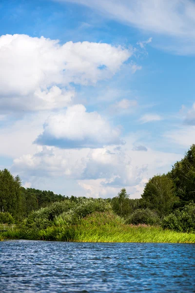 Ciel bleu et nuages blancs, forêt verte et eaux bleues de la rivière — Photo