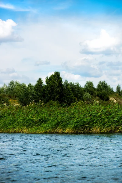 Ciel bleu et nuages blancs, forêt verte et eaux bleues de la rivière — Photo