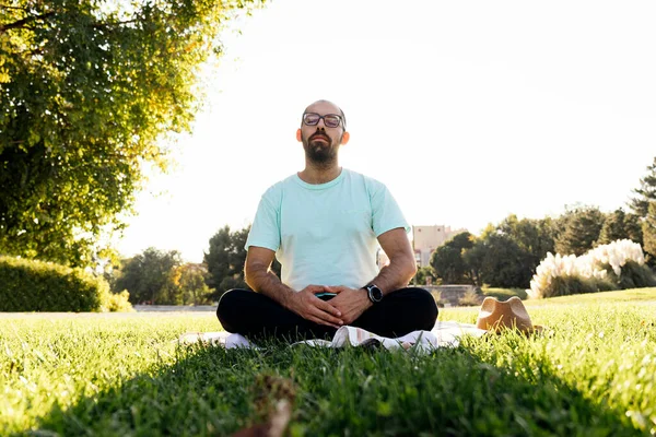 Man meditating at sunset on a tablecloth in the meadow one afternoon on a picnic day