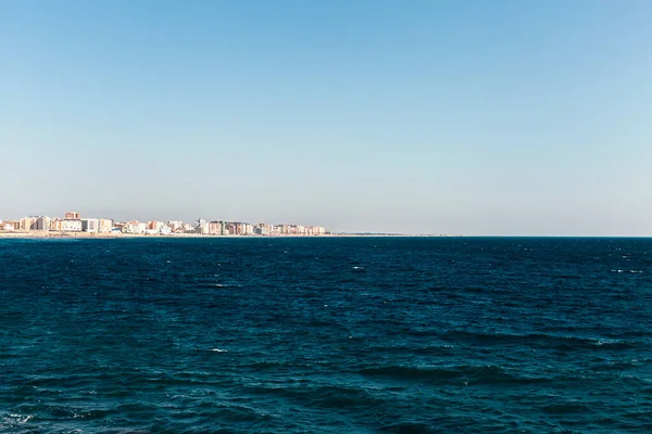 波の多い海と午後を背景に都市と海岸線の景色のストック写真 — ストック写真