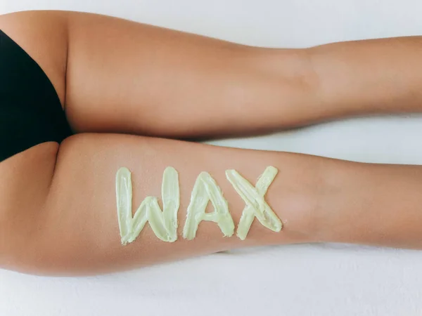 Top view on inscription wax laid out with hot wax for depilation. Hair removal procedure on female thighs. The concept of depilation, epilation, waxing, shugaring.