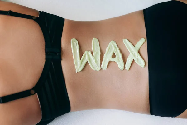 Top view on inscription wax laid out with hot wax for depilation. Hair removal procedure on female back. The concept of depilation, epilation, waxing, shugaring.