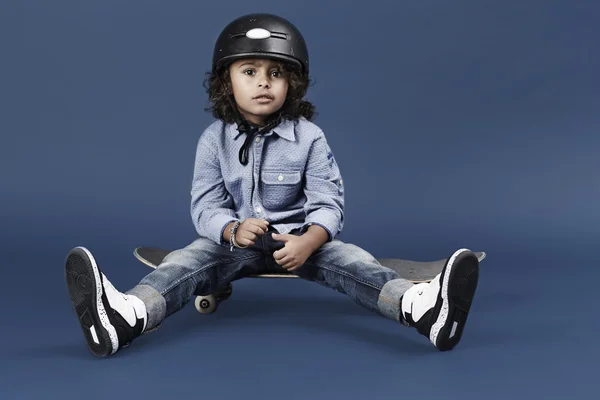 Skateboarder sitting on board — Stock Photo, Image