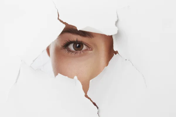 Girl looking through ripped paper — Stock Photo, Image