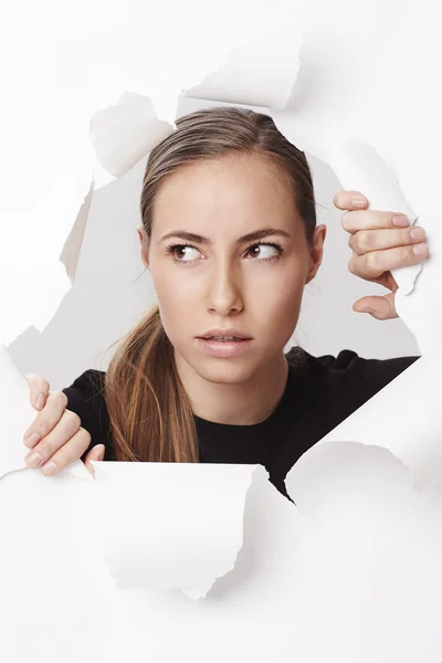 Woman looking through ripped paper — Stock Photo, Image