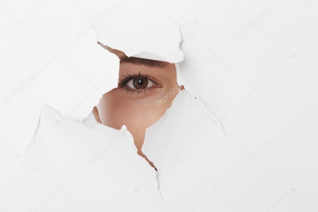 woman looking through torn page